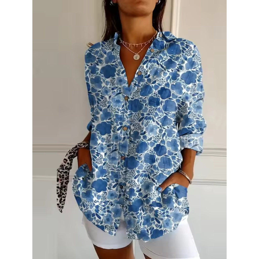 Chemise femme à motifs floraux bleus, manches longues, col ouvert, portée avec short blanc. Style décontracté et tendance pour l'été.