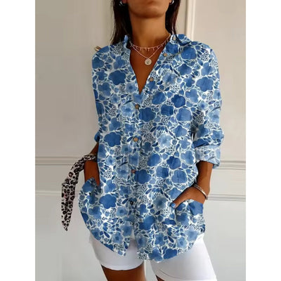 Chemise femme à motifs floraux bleus, manches longues, col ouvert, portée avec short blanc. Style décontracté et tendance pour l'été.
