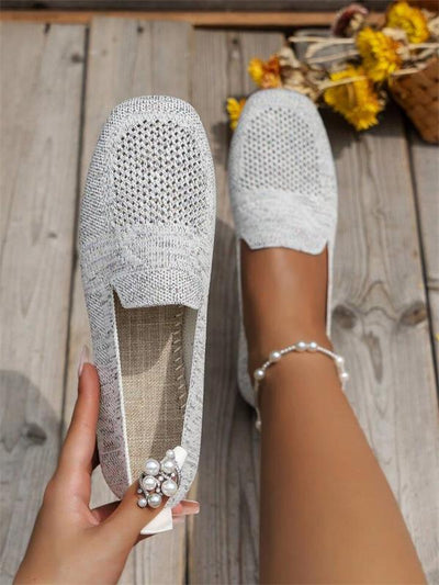 Chaussures en tricot blanc pour femme sur plancher en bois, avec décoration perles. Mode estivale, confort, style décontracté.