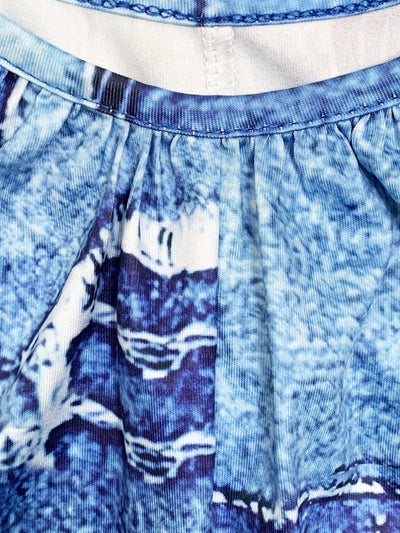 Jupe en jean bleu avec motif abstrait blanc et bleu foncé, plis élégants, tissu texturé. Mode féminine, style décontracté, tendance actuelle.