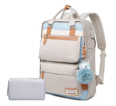 Sac à dos beige et bleu avec pompon, porte-clés licorne, détails en cuir marron, accompagné d'une trousse grise. Accessoire mode tendance.