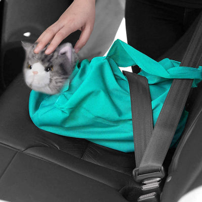 Main en train de placer un chat en peluche dans un sac turquoise sur un siège de voiture. Jouet chat réaliste, sécurité voiture, accessoire voyage.