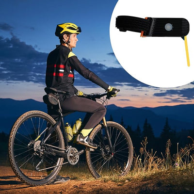 Cycliste en tenue de sécurité sur un vélo de montagne au crépuscule, avec un gros plan d'une lampe de vélo LED. Paysage montagneux en arrière-plan.