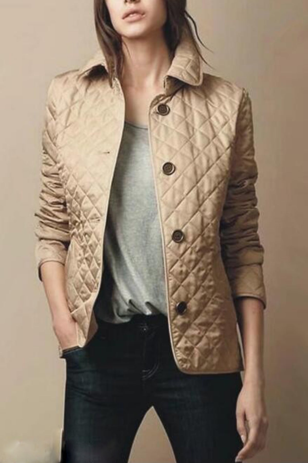 Femme portant une veste matelassée beige, col relevé, boutons noirs, sur un t-shirt gris et un jean foncé. Mode automne, style décontracté.