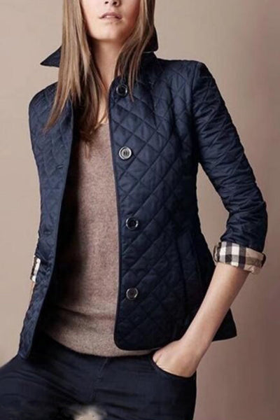 Veste matelassée bleu marine pour femme, manches retroussées, col relevé, boutons visibles, style élégant et moderne, tenue automne-hiver.