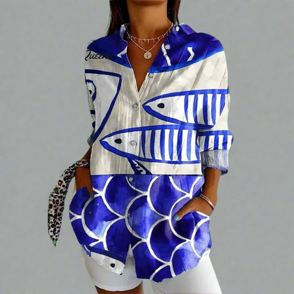 Chemise femme à motifs poissons bleus et blancs, manches longues, col ouvert, poches avant, style décontracté, sur fond gris.