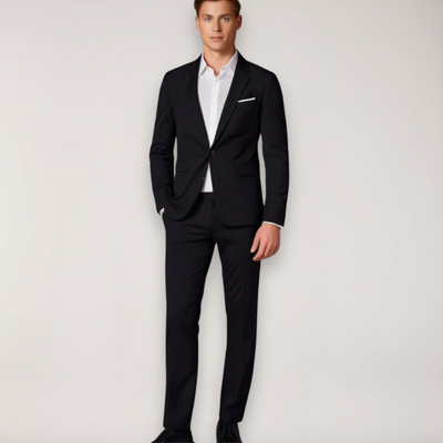 Homme en costume noir élégant, chemise blanche, posant debout. Mode masculine, tenue formelle, style classique, vêtements de cérémonie.