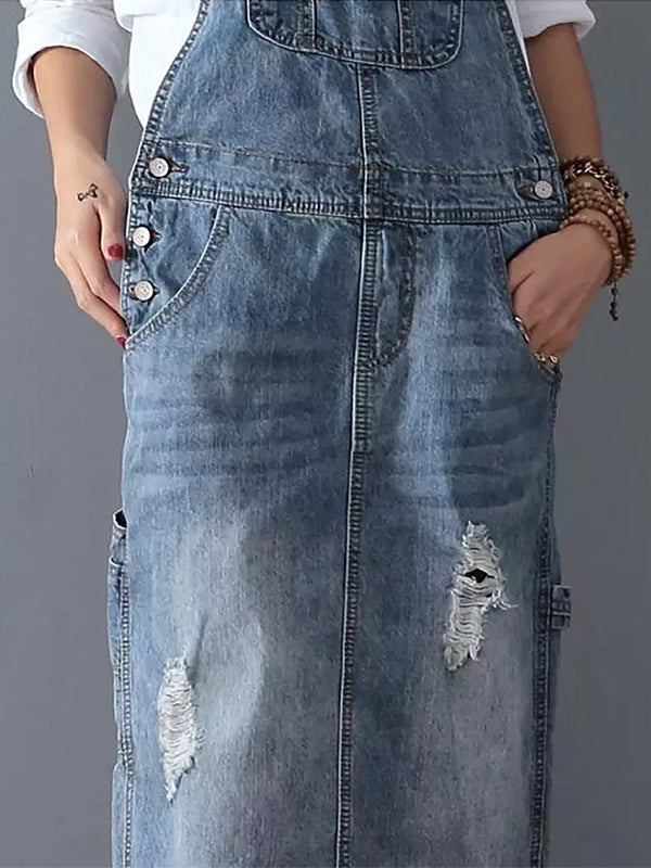Robe salopette en jean bleu délavé avec poches, boutons argentés et détails déchirés. Mode décontractée, tendance denim, style urbain.