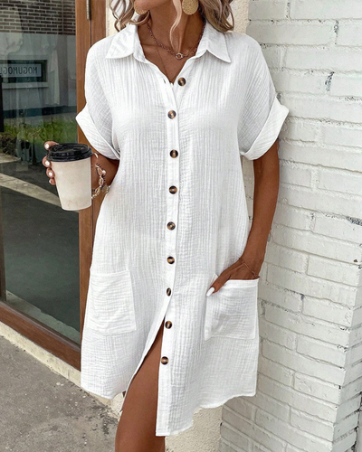 Robe chemise blanche en lin avec boutons en bois, manches courtes retroussées, poches avant, tenue d'été décontractée, femme tenant un café.