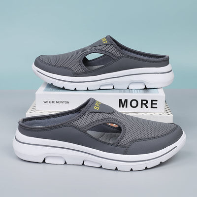 Chaussures de sport grises en maille respirante, semelle blanche antidérapante, posées sur des livres, design moderne et confortable.