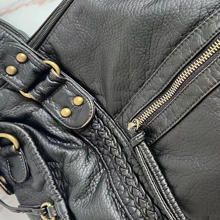 Sac à main en cuir noir avec fermeture éclair dorée et détails tressés, style élégant et moderne, accessoire mode femme tendance.