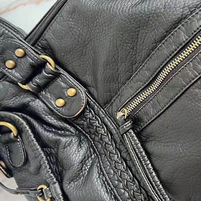Sac à main en cuir noir avec fermeture éclair dorée et détails tressés, style élégant et moderne, accessoire mode femme tendance.