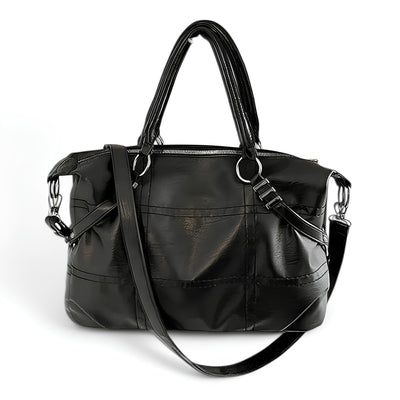 Sac à main en cuir noir élégant avec bandoulière réglable, fermetures éclair argentées et poignées doubles. Accessoire mode femme chic et pratique.