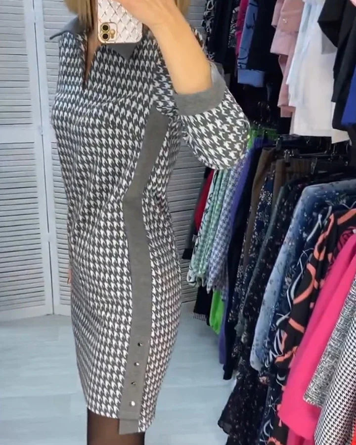 Robe à motif pied-de-poule gris et blanc, manches longues, col chemise, dans une boutique de vêtements, avec portemanteaux colorés en arrière-plan.