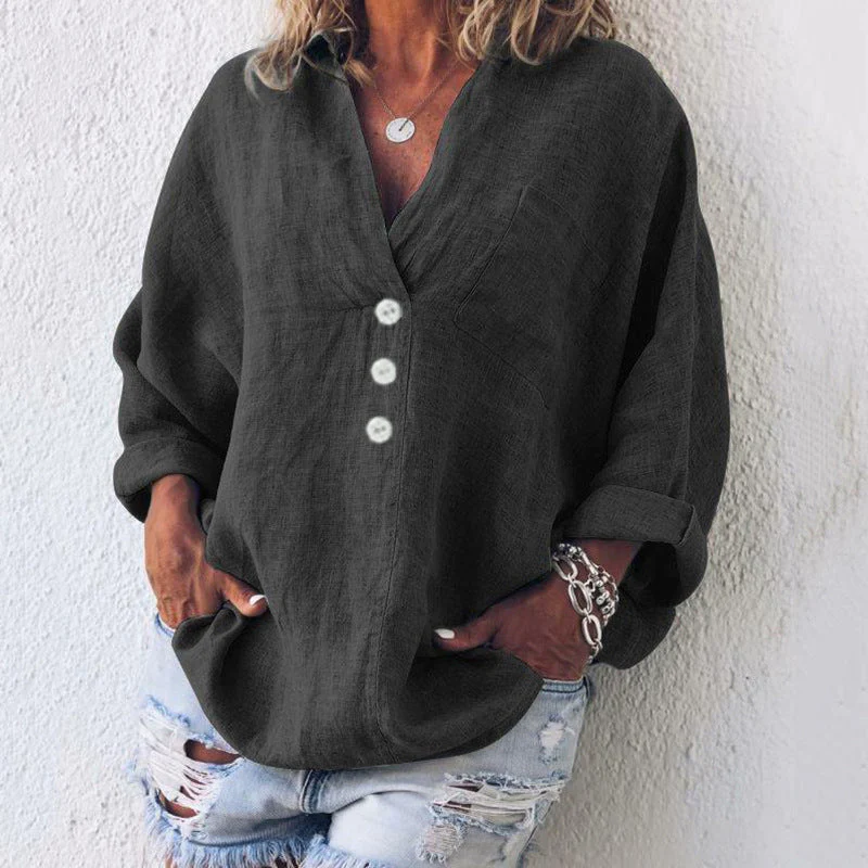 Femme portant une chemise noire ample avec boutons blancs, manches retroussées, associée à un jean déchiré. Mode décontractée, tendance et élégante.