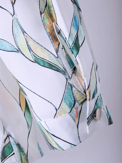Manche de chemise blanche à motifs feuilles vertes et bleues, bouton argenté, tissu léger. Mode élégante, tendance printemps-été.