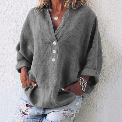Femme portant une chemise en lin gris avec boutons blancs, manches retroussées, associée à un jean déchiré. Style décontracté et tendance.