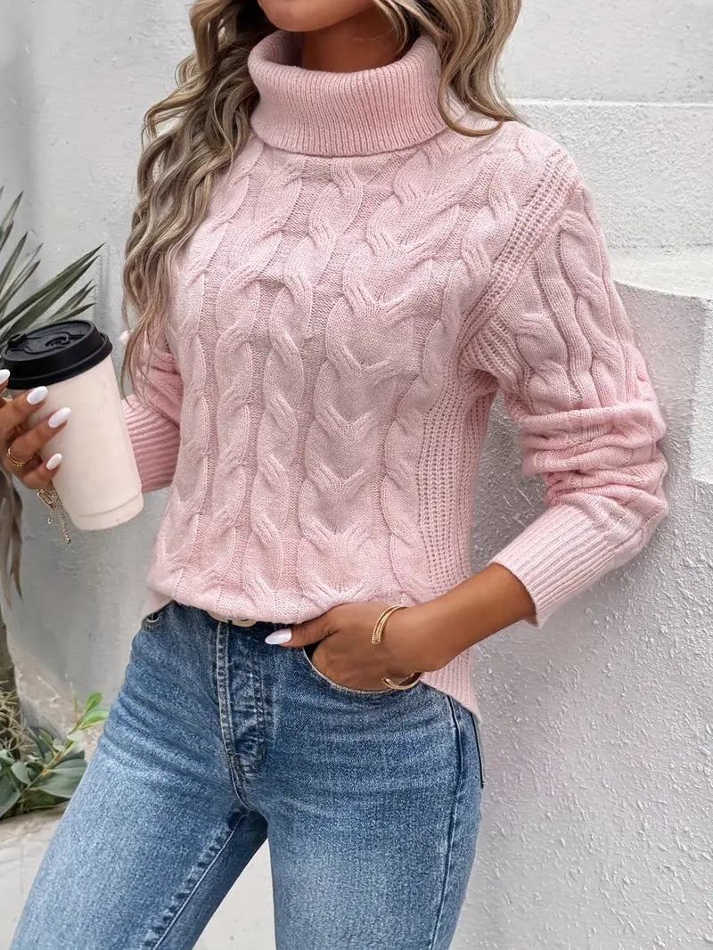 Femme portant un pull rose à col roulé torsadé, tenant un gobelet de café, jeans bleu, style décontracté, mode automne-hiver tendance.