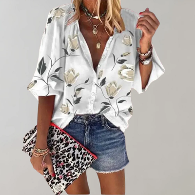 Femme portant une chemise à fleurs blanches et beiges, short en jean, tenant une pochette léopard. Mode estivale, style décontracté chic.