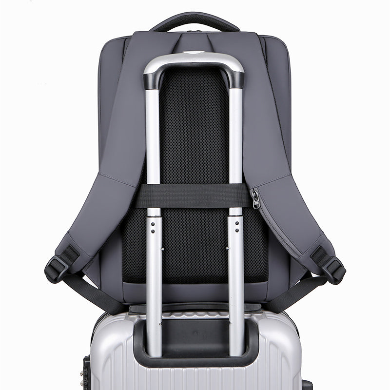 Sac à dos gris fixé sur une valise à roulettes argentée, montrant des bretelles et une poignée télescopique. Voyage, bagage, transport pratique.
