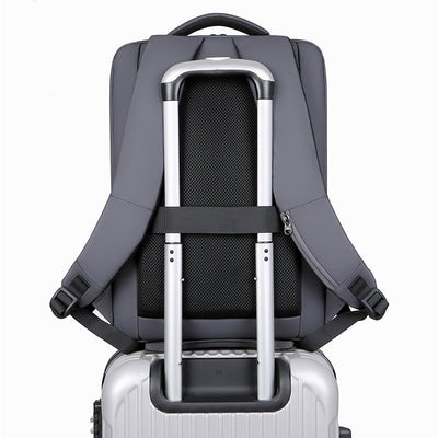 Sac à dos gris fixé sur une valise à roulettes argentée, montrant des bretelles et une poignée télescopique. Voyage, bagage, transport pratique.