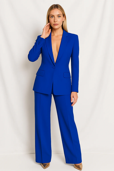 Femme en tailleur bleu électrique, veste ajustée et pantalon large, pose devant un fond blanc. Mode élégante, tendance, tenue professionnelle.