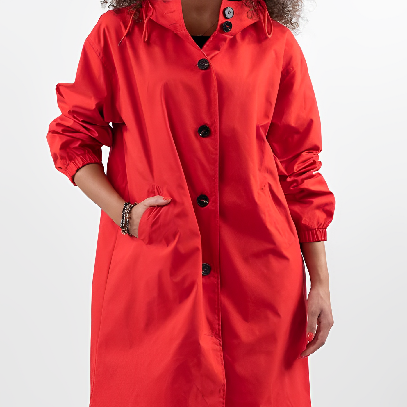 Femme portant un manteau rouge vif avec boutons noirs, style moderne et élégant, mode automne-hiver, manches longues, fond blanc.
