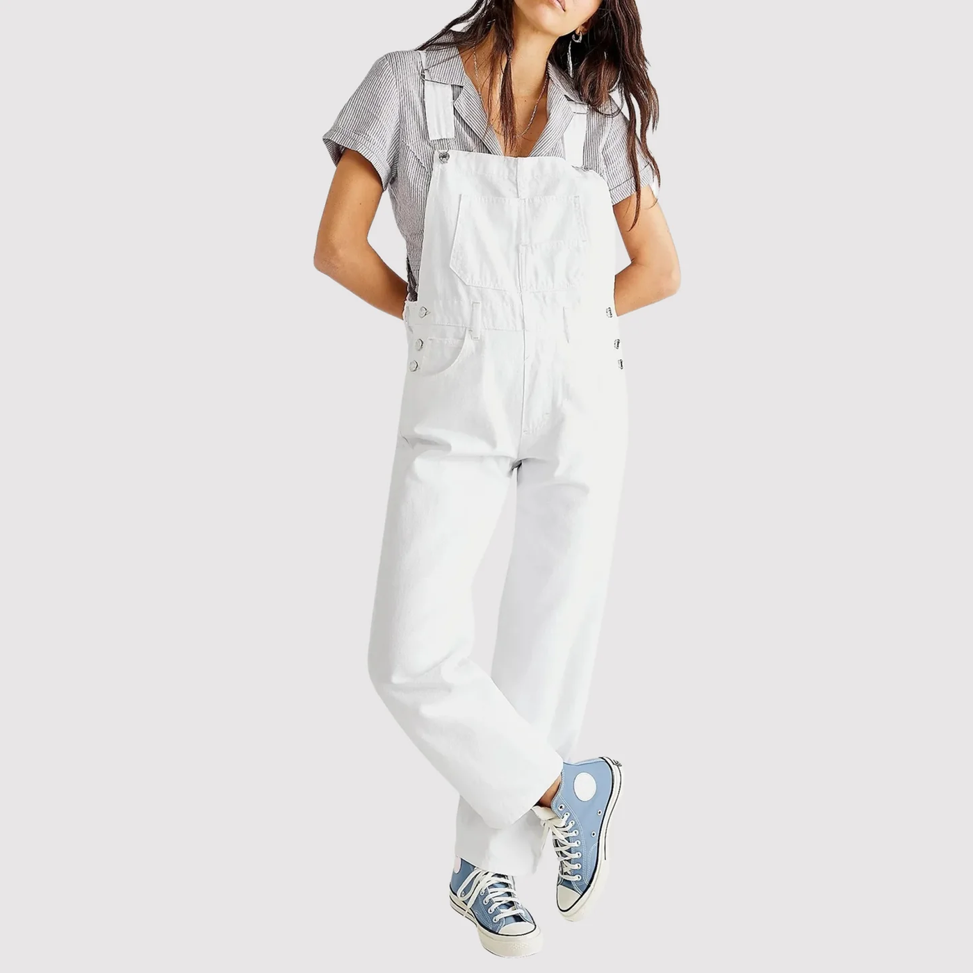 Femme portant une salopette blanche et une chemise à carreaux, baskets bleues. Mode décontractée, tenue tendance, style urbain.