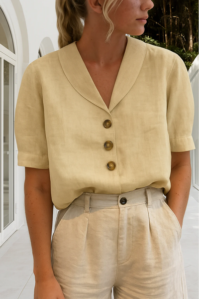 Femme portant une chemise beige en lin avec col en V et boutons marron, assortie à un pantalon beige, dans un cadre moderne et lumineux.