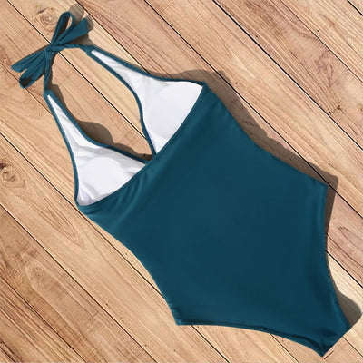 Maillot de bain une pièce bleu canard sur plancher en bois, design dos nu avec nœud, idéal pour plage et piscine, mode été femme.