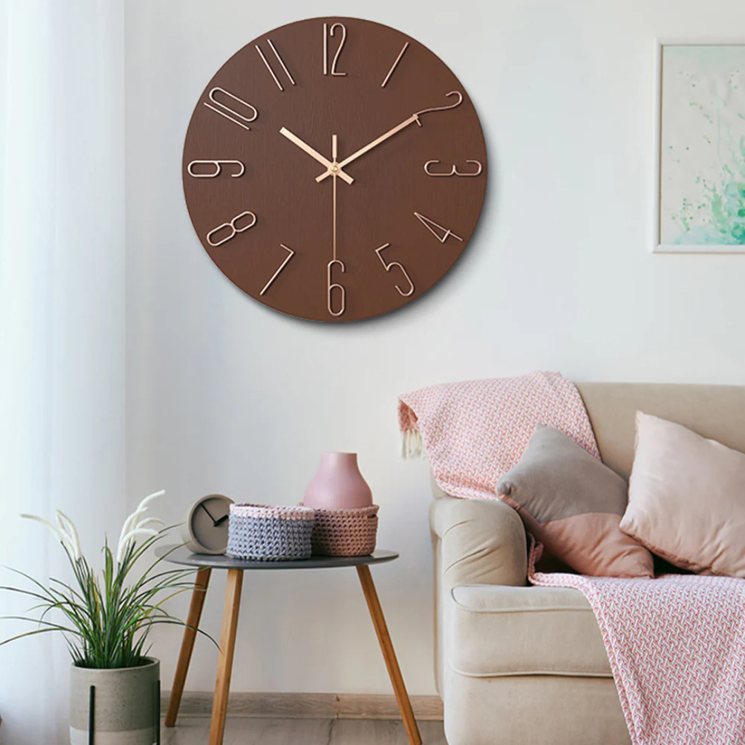 Horloge murale marron moderne avec chiffres dorés, accrochée dans un salon élégant avec canapé beige, coussins et table d'appoint en bois.