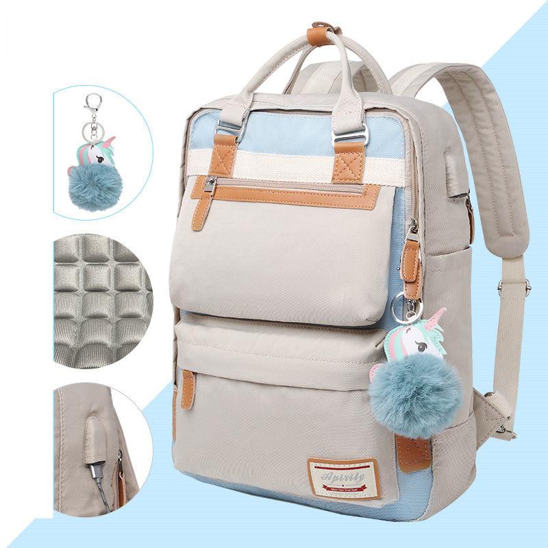 Sac à dos beige et bleu avec porte-clés licorne, poches multiples, détails en cuir marron, design moderne. Accessoire mode pratique et tendance.