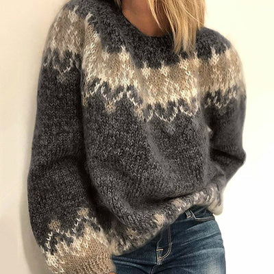 Pull en laine épaisse gris avec motifs géométriques beige et blanc, manches longues, porté par une femme, style automne-hiver tendance.