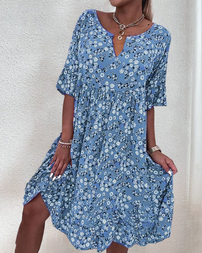 Robe d'été bleue à motifs floraux, manches courtes, col en V, portée par une femme. Mode féminine, tenue décontractée, style estival élégant.