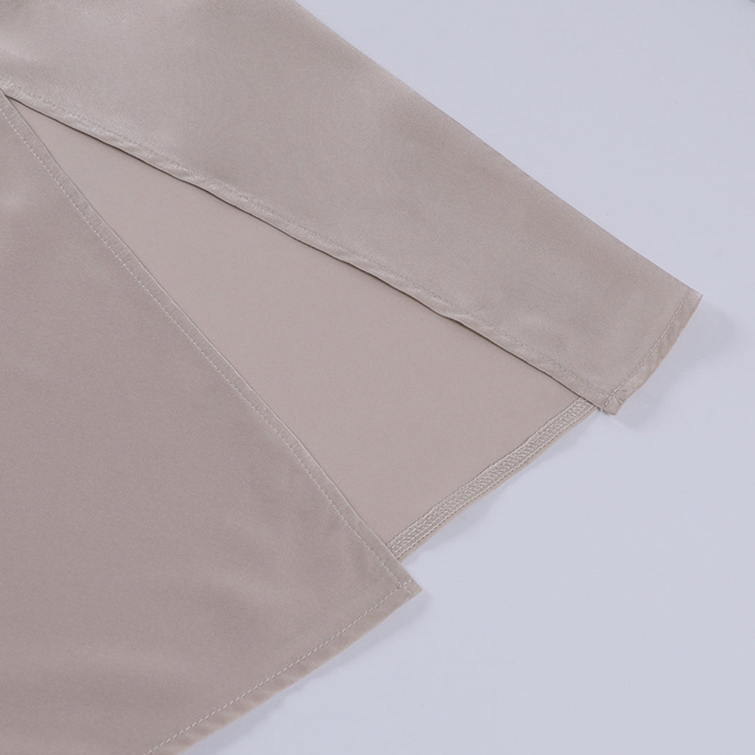 Manche de chemisier en satin beige, tissu doux et brillant, gros plan. Mode élégante, vêtement féminin, texture soyeuse, tendance actuelle.