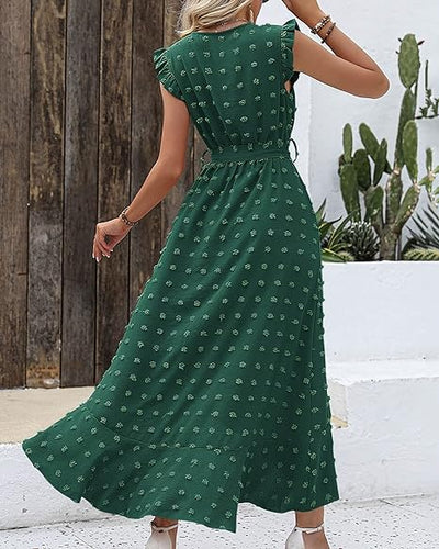 Robe longue verte à motifs floraux, manches courtes, ceinture à la taille, femme de dos, fond extérieur avec cactus et mur en bois.