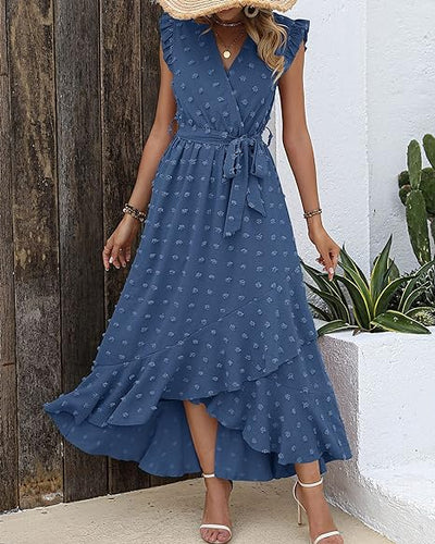 Robe longue bleue à motifs floraux, ceinture nouée, manches à volants, portée par une femme. Style élégant et estival, parfait pour les occasions décontractées.