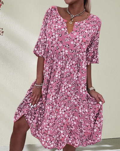 Robe rose à motifs floraux, manches courtes, col rond, portée par une femme. Mode féminine, style estival, tenue décontractée élégante.