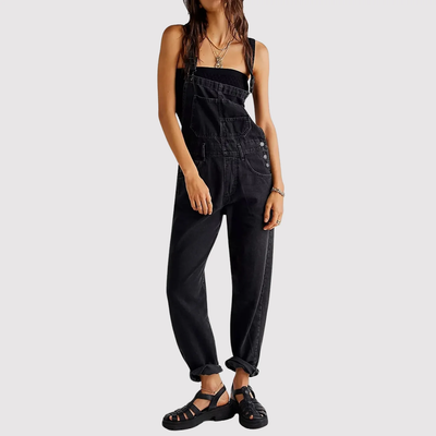Femme portant une salopette noire en denim, style décontracté, avec sandales noires. Mode féminine tendance, tenue urbaine chic.