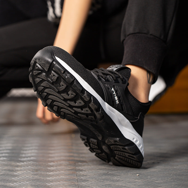 Chaussure de sport noire avec semelle antidérapante, design moderne, portée par une personne sur sol métallique. Idéale pour course et fitness.