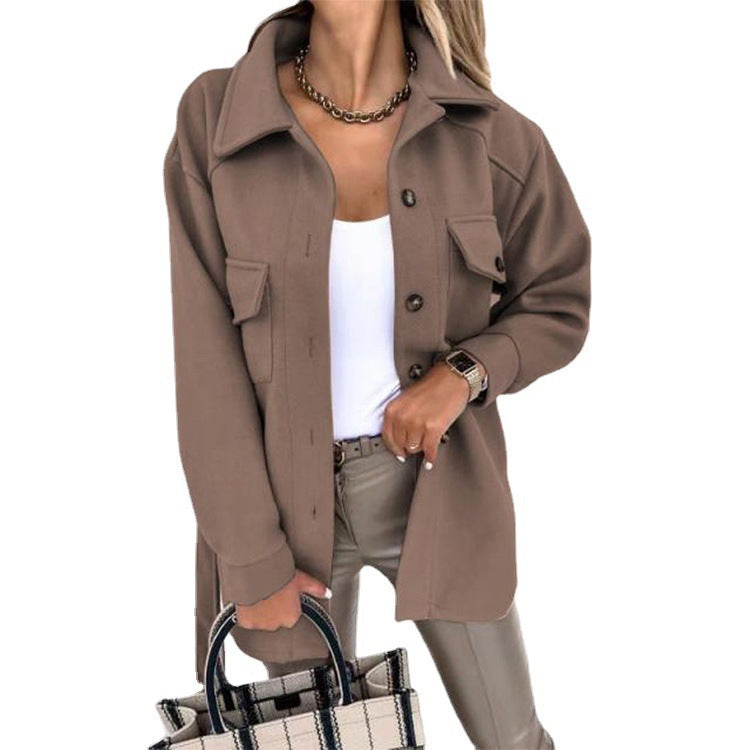 Femme portant une surchemise marron tendance, chemise blanche, pantalon beige, collier doré, tenant un sac à carreaux. Mode automne chic.