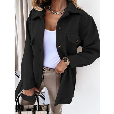 Femme portant une veste noire élégante, chemise blanche, pantalon beige, avec un sac à main à carreaux. Mode automne chic, style urbain tendance.