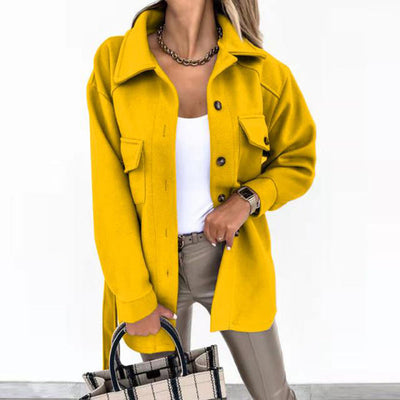 Femme portant une veste jaune tendance, chemise blanche et pantalon beige, tenant un sac à main à carreaux. Mode automne, style chic et moderne.