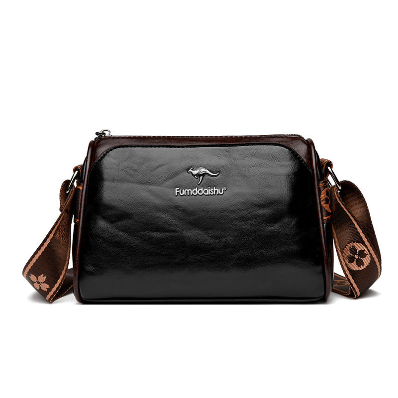 Sac à bandoulière en cuir noir brillant avec logo kangourou, sangle marron à motifs floraux, design élégant et moderne pour femmes.
