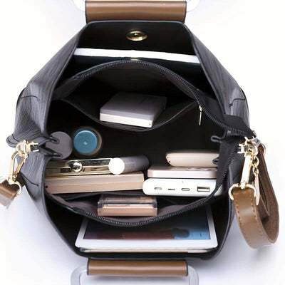 Sac à main ouvert en cuir marron avec compartiments, contenant smartphone, tablette, rouge à lèvres, portefeuille, chargeur portable et miroir.