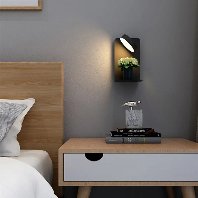 Lampe murale moderne éclairant une table de chevet en bois avec livres et décoration, dans une chambre contemporaine. Éclairage intérieur design.