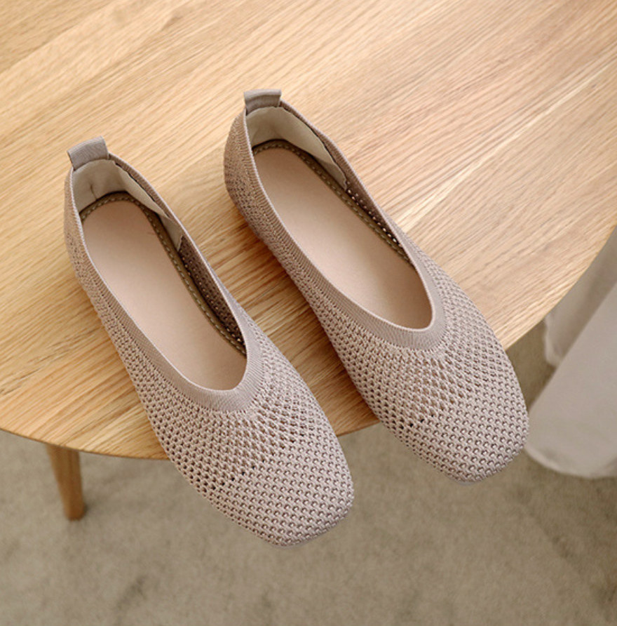 Ballerines beiges en maille sur table en bois, chaussures confortables et élégantes pour femmes, design moderne et respirant.
