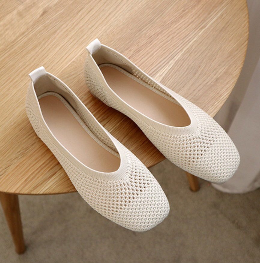 Ballerines blanches en maille respirante sur une table en bois, chaussures plates élégantes pour femmes, mode confortable et tendance.