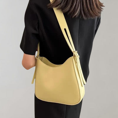 Sac à bandoulière jaune porté par une femme en robe noire, design moderne et élégant, accessoire de mode tendance, style minimaliste.