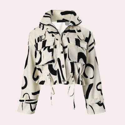 Veste courte à motifs abstraits noirs sur fond blanc, avec poches à rabat et cordons de serrage. Style moderne et tendance pour femme.